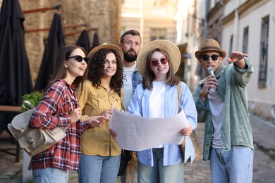 Photo of Guide with microphone and group of tourists on city street during excursion