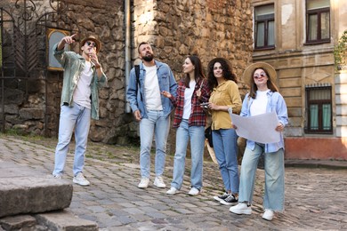 Photo of Guide with microphone and group of tourists on city street during excursion