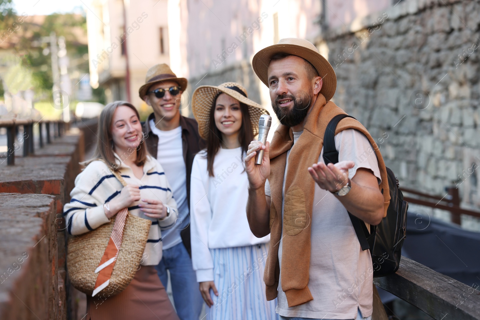 Guide with microphone and tourists on city street during excursion Photo of Guide with microphone and tourists on city street during excursion