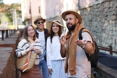 Photo of Guide with microphone and tourists on city street during excursion