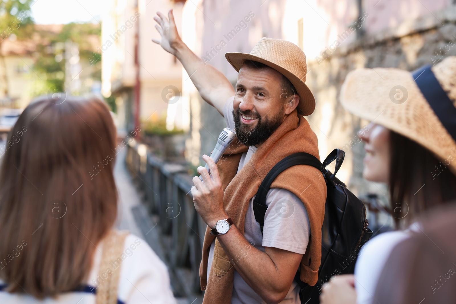 Guide with microphone and tourists on city street during excursion Photo of Guide with microphone and tourists on city street during excursion