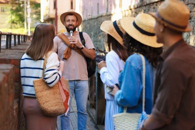 Photo of Guide with microphone and group of tourists on city street during excursion
