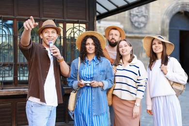 Photo of Guide with microphone and group of tourists on city street during excursion
