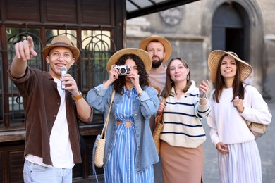Photo of Guide with microphone and group of tourists on city street during excursion