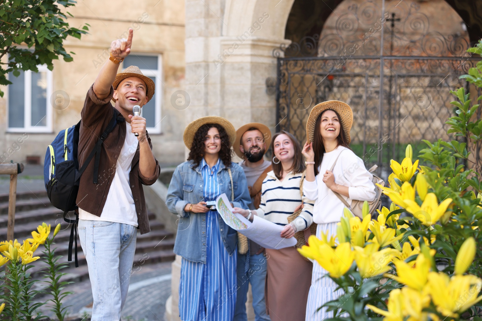 Guide with microphone and group of tourists on city street during excursion Photo of Guide with microphone and group of tourists on city street during excursion