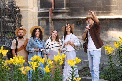Photo of Guide with microphone and group of tourists on city street during excursion