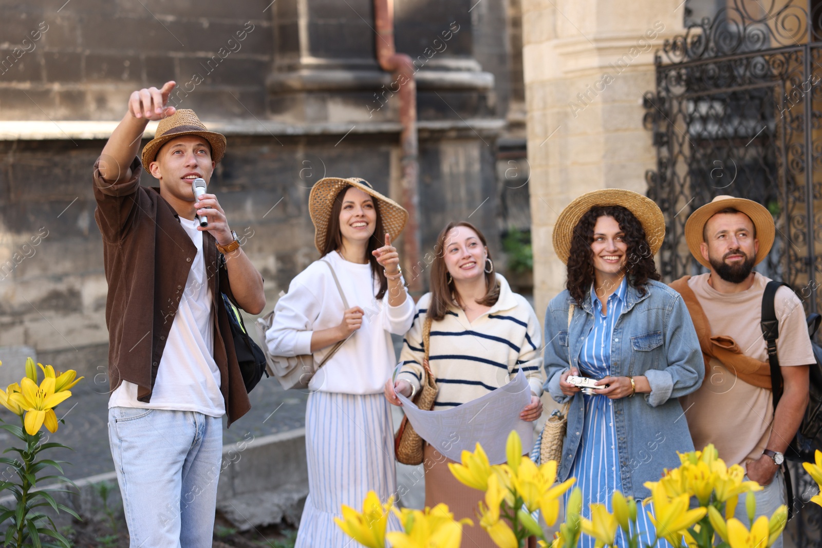 Guide with microphone and group of tourists on city street during excursion Photo of Guide with microphone and group of tourists on city street during excursion