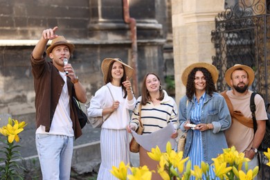 Photo of Guide with microphone and group of tourists on city street during excursion