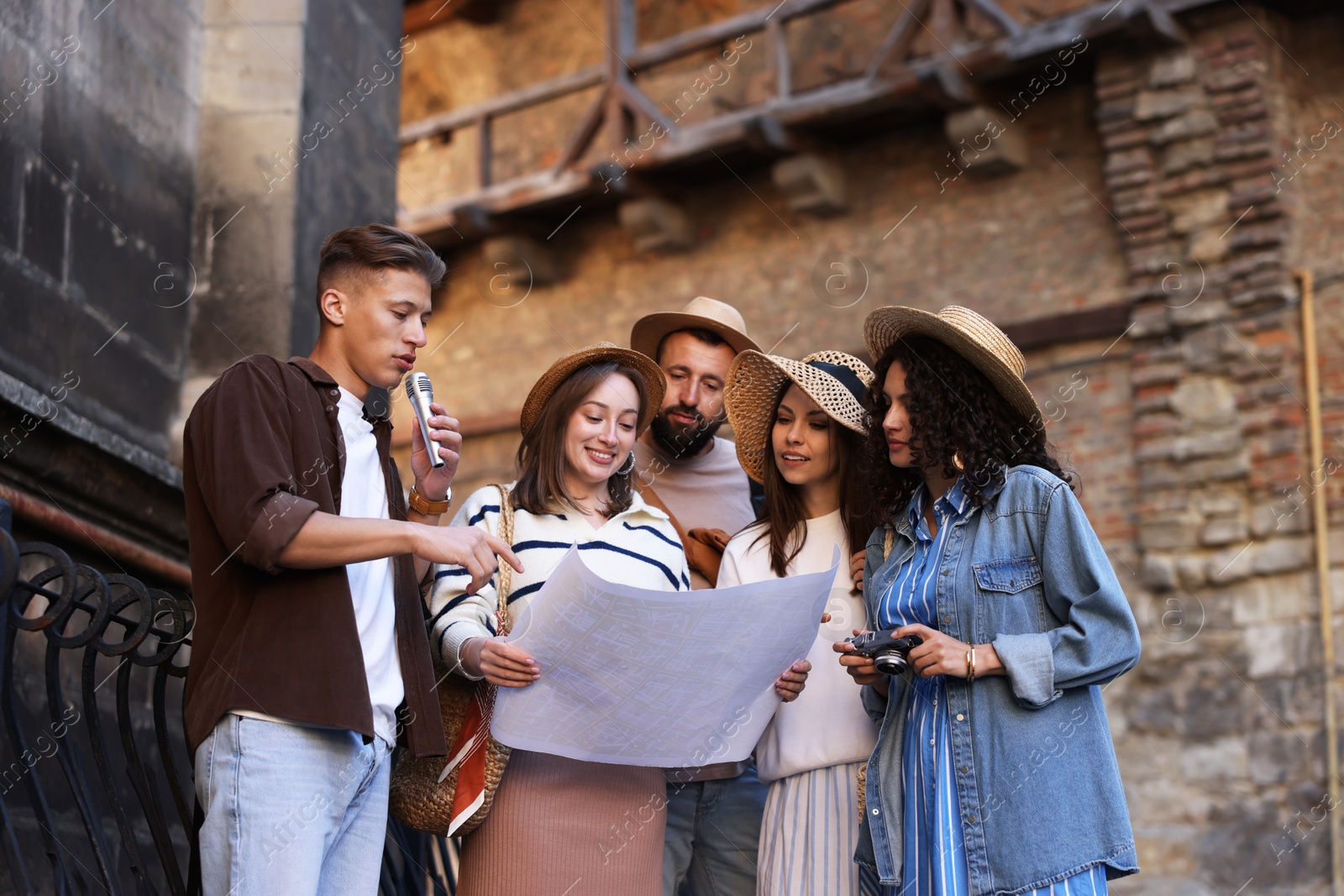 Guide with microphone and group of tourists on city street during excursion, low angle view Photo of Guide with microphone and group of tourists on city street during excursion, low angle view