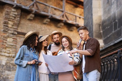Photo of Guide with microphone and group of tourists on city street during excursion, low angle view