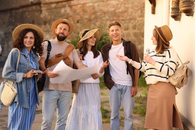 Photo of Guide with microphone and group of tourists on city street during excursion