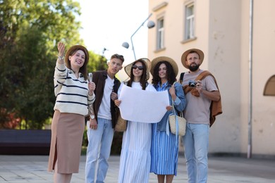 Photo of Guide with microphone and group of tourists on city street during excursion
