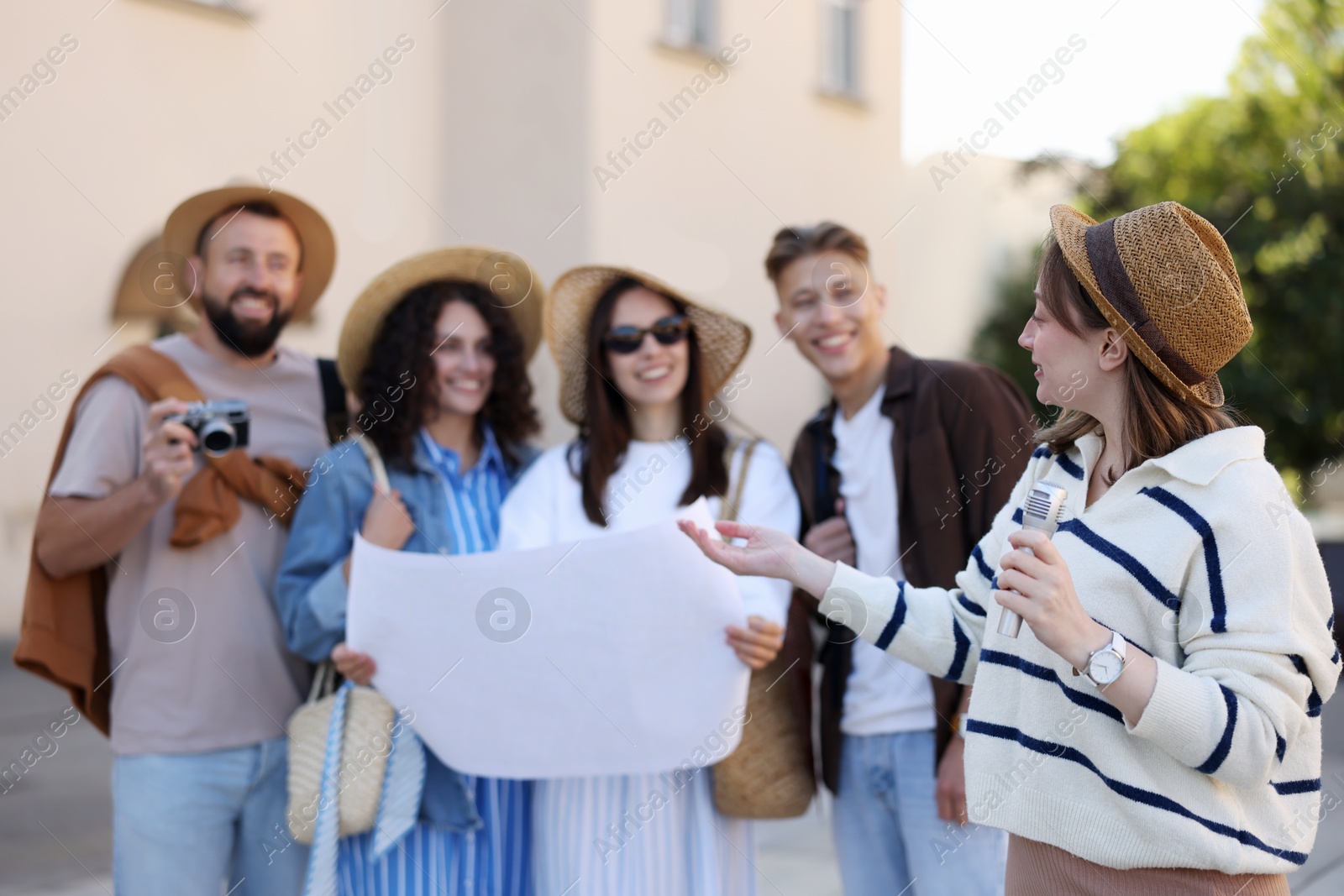 Guide with microphone and group of tourists on city street during excursion, selective focus Photo of Guide with microphone and group of tourists on city street during excursion, selective focus