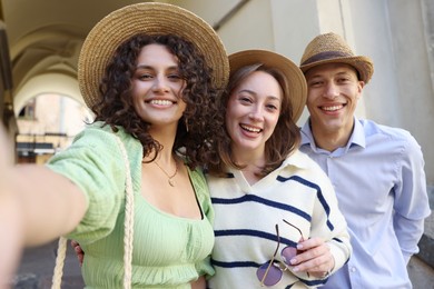 Photo of Tourists in straw hats taking selfie on city street