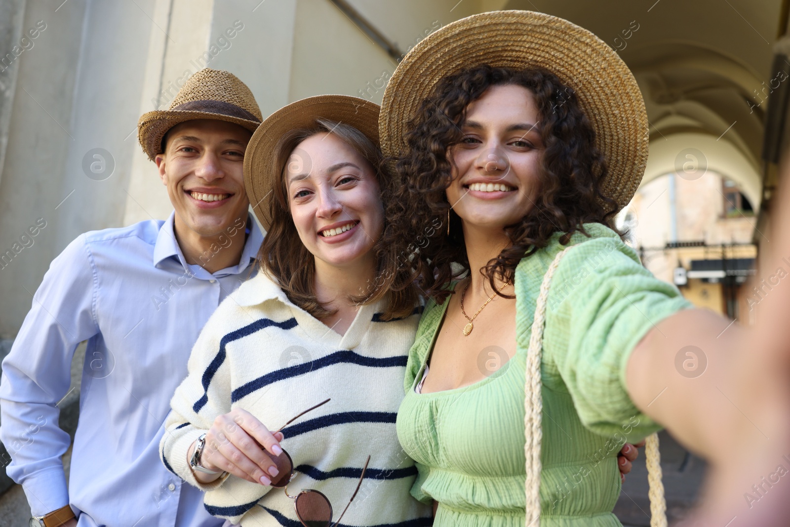 Tourists in straw hats taking selfie on city street Photo of Tourists in straw hats taking selfie on city street