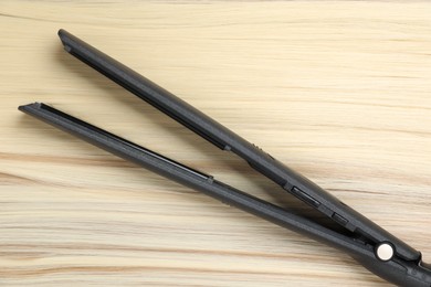 Photo of Modern flat iron on shiny blonde hair, top view