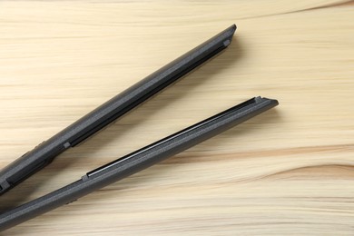 Photo of Modern flat iron on shiny blonde hair, top view