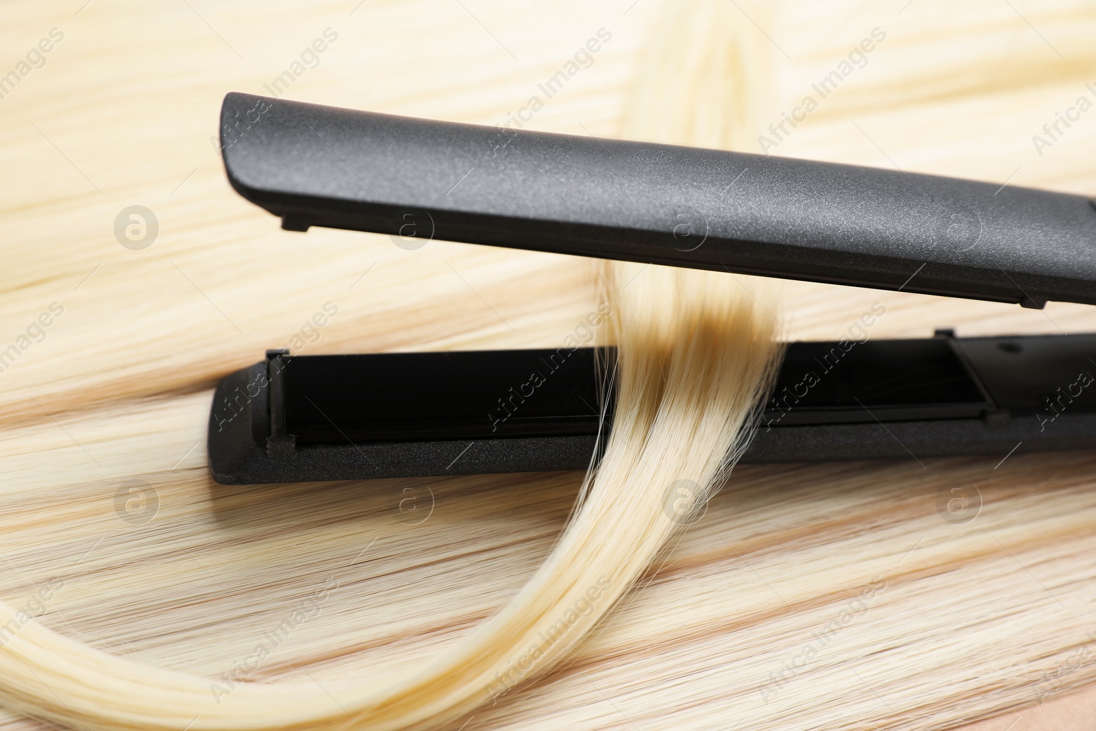 Modern flat iron on shiny blonde hair, closeup Photo of Modern flat iron on shiny blonde hair, closeup