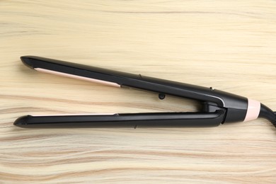 Photo of Modern flat iron on shiny blonde hair, top view