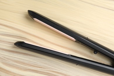 Photo of Modern flat iron on shiny blonde hair, top view
