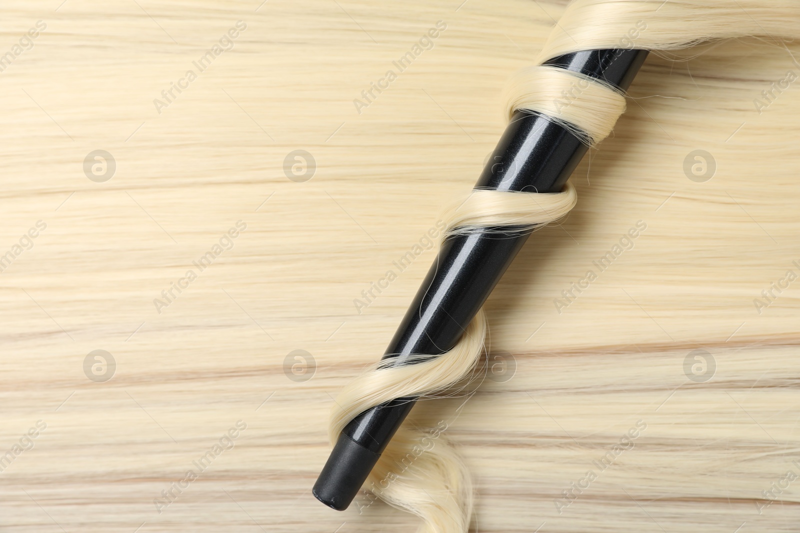 Curling iron with shiny blonde hair, top view Photo of Curling iron with shiny blonde hair, top view