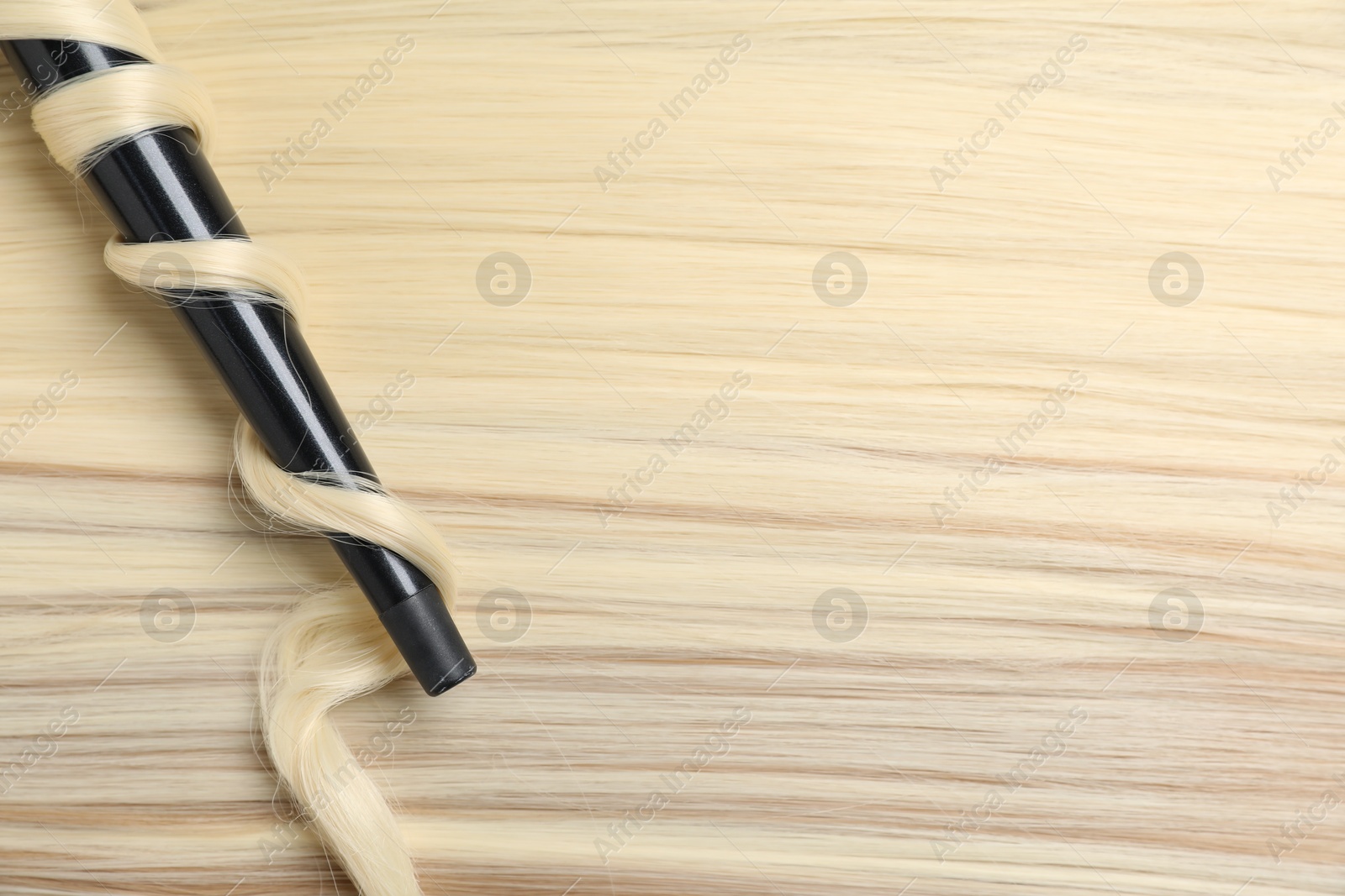 Curling iron with shiny blonde hair, top view Photo of Curling iron with shiny blonde hair, top view
