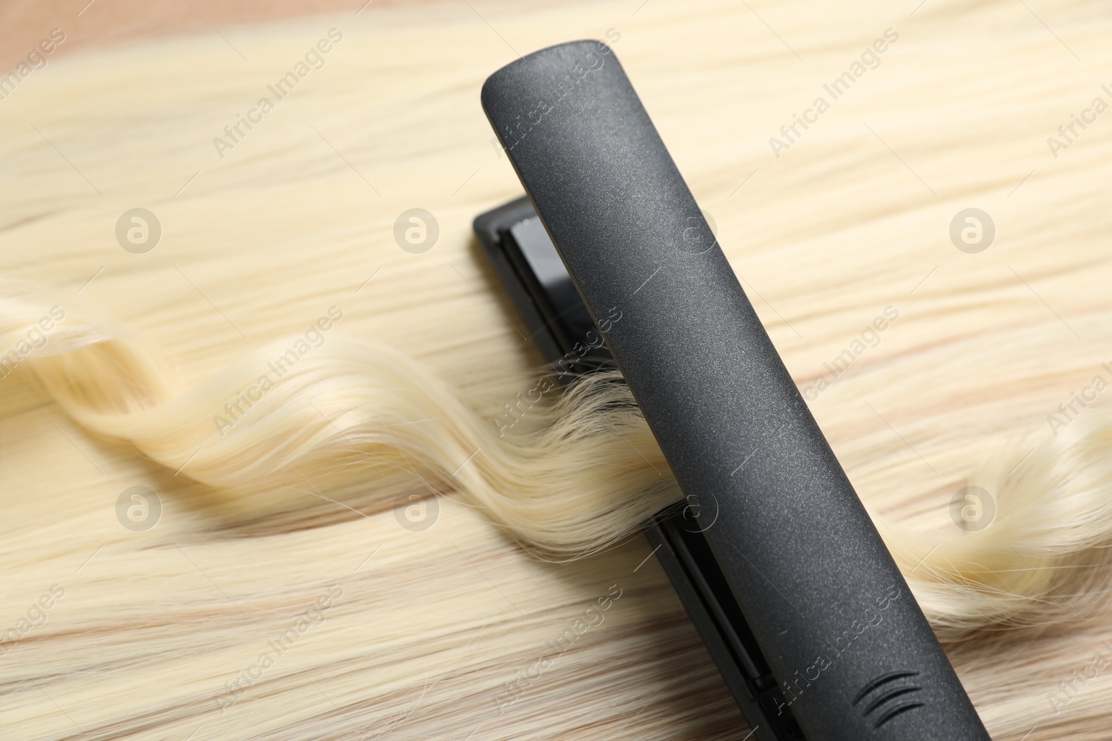 Modern flat iron on shiny blonde hair, closeup Photo of Modern flat iron on shiny blonde hair, closeup