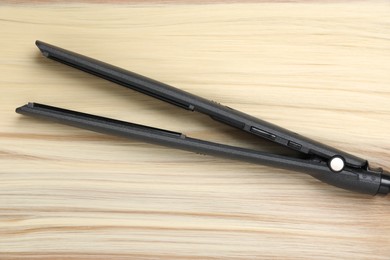 Photo of Modern flat iron on shiny blonde hair, top view