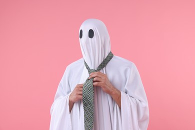 Photo of Man in ghost costume adjusting tie on pink background