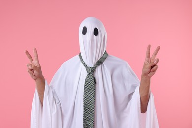 Photo of Man in ghost costume with tie showing V-signs on pink background