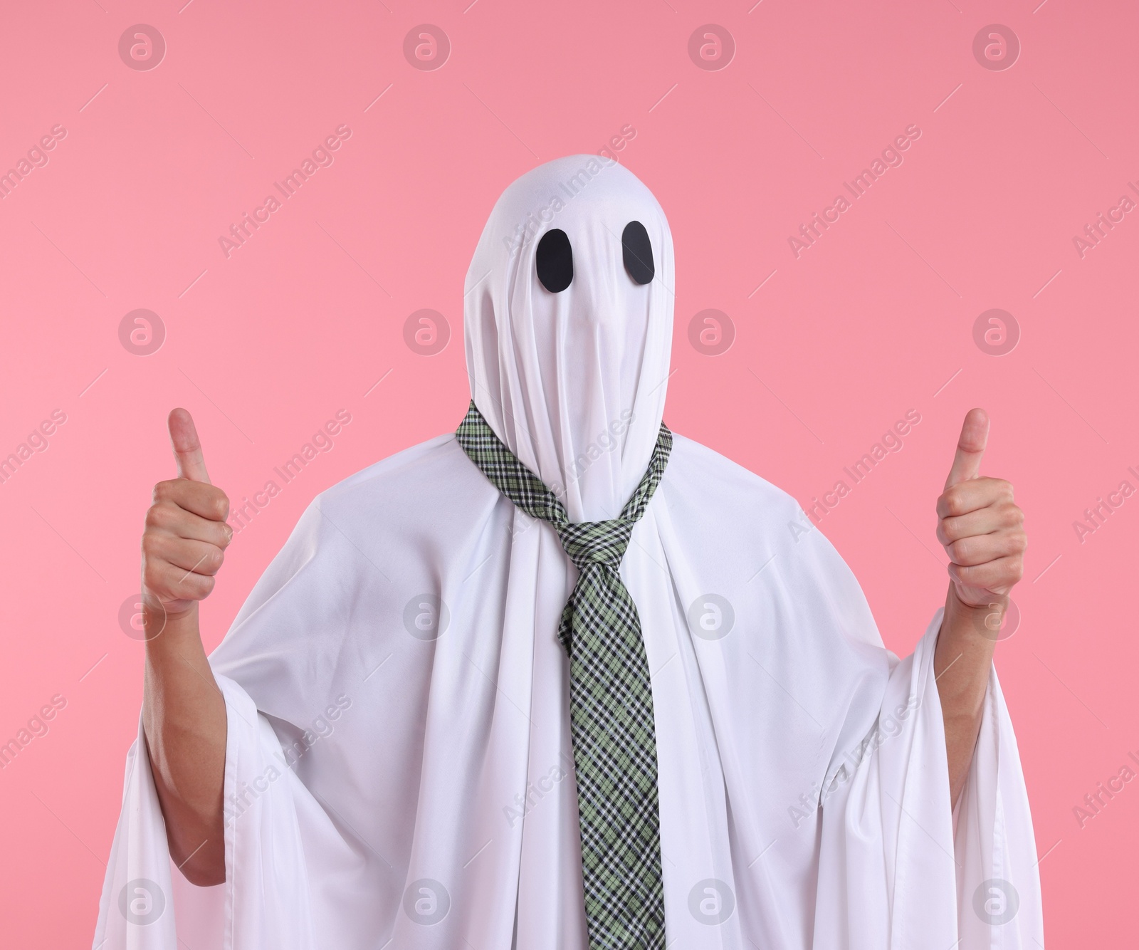 Photo of Man in ghost costume with tie showing thumbs up on pink background