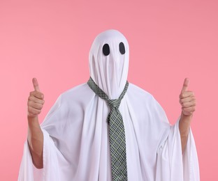 Photo of Man in ghost costume with tie showing thumbs up on pink background