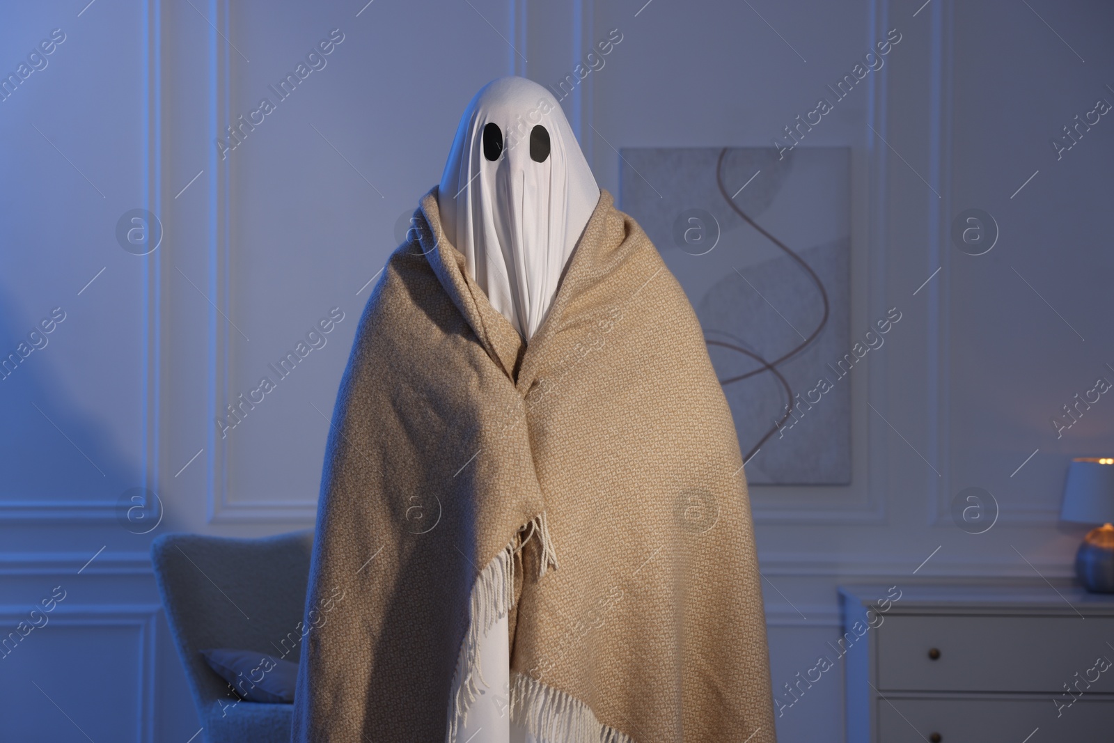 Photo of Man in ghost costume wrapped with blanket at home