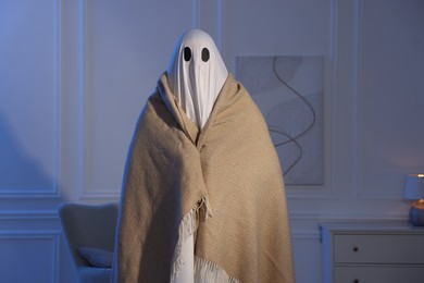 Photo of Man in ghost costume wrapped with blanket at home