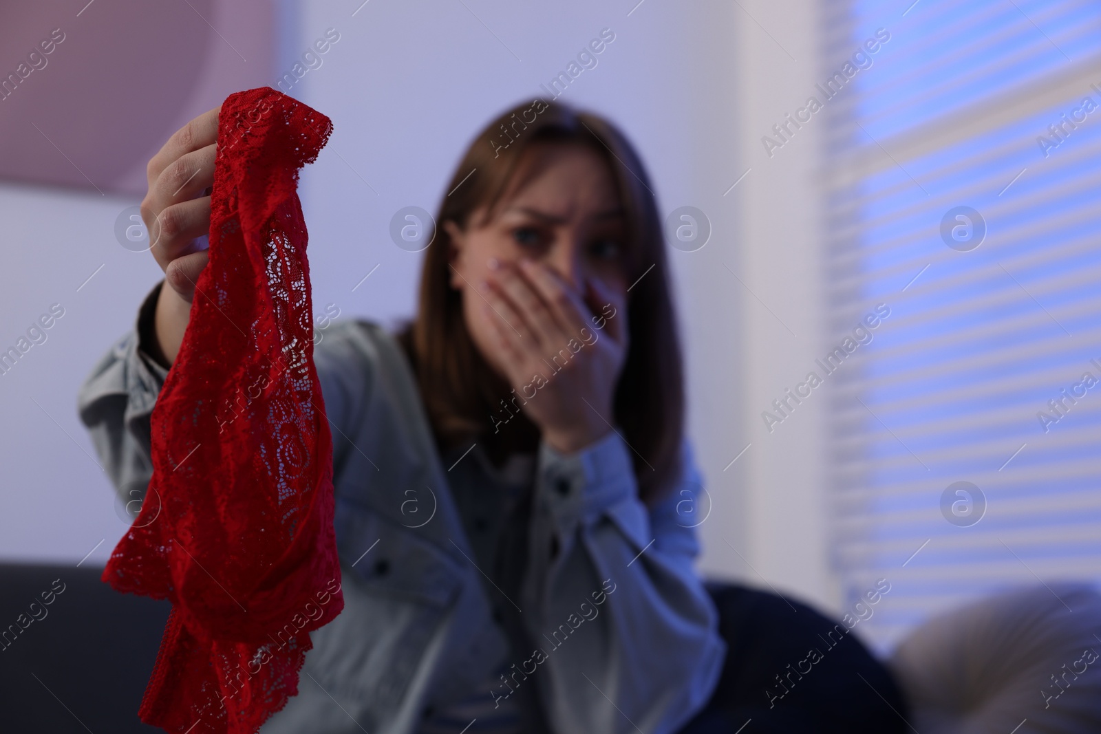 Photo of Betrayal. Shocked wife finding mistress panties at home, selective focus