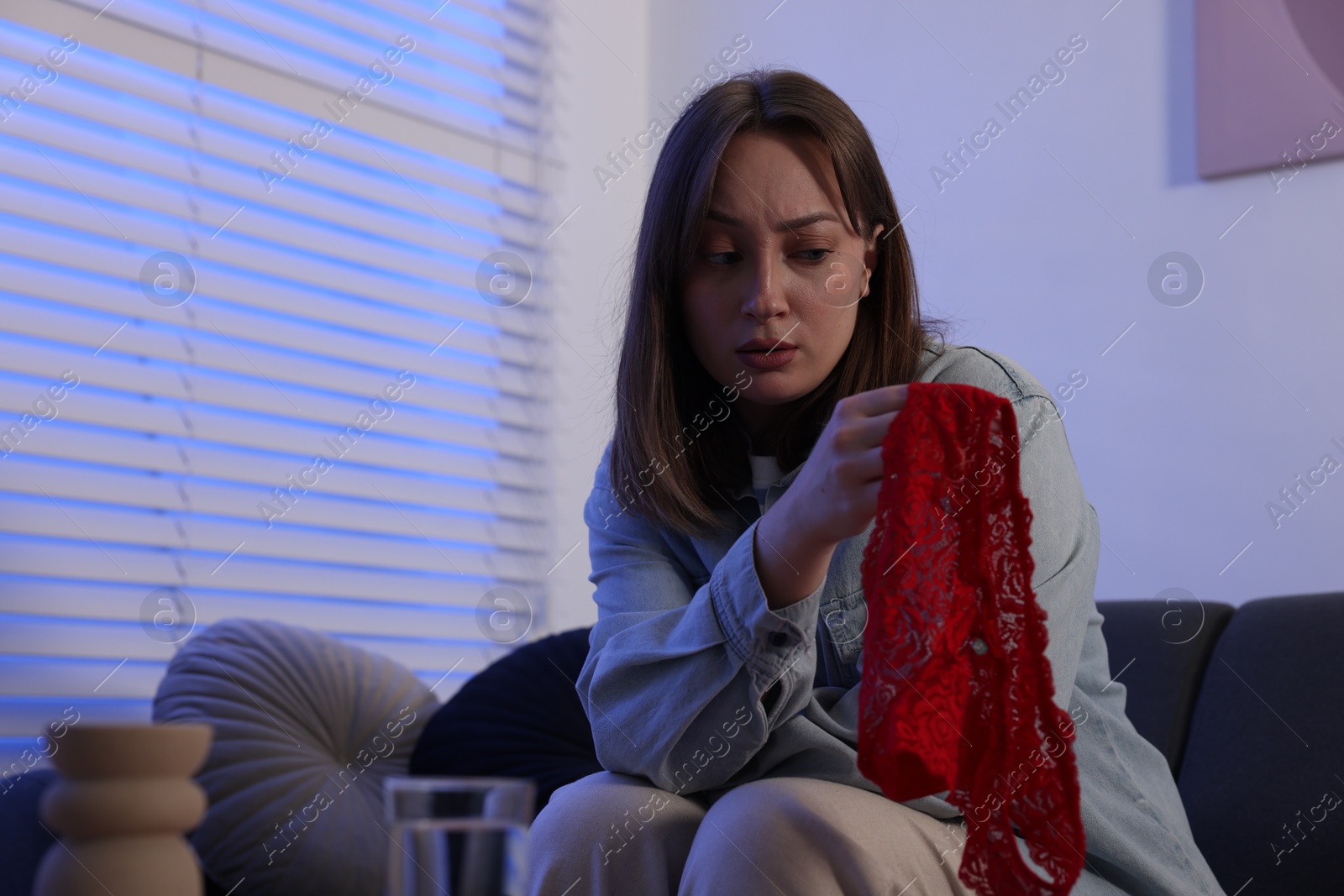 Photo of Betrayal. Frustrated wife with mistress panties on sofa at home