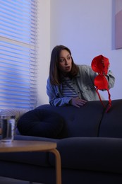 Photo of Betrayal. Shocked wife finding mistress bra near sofa at home