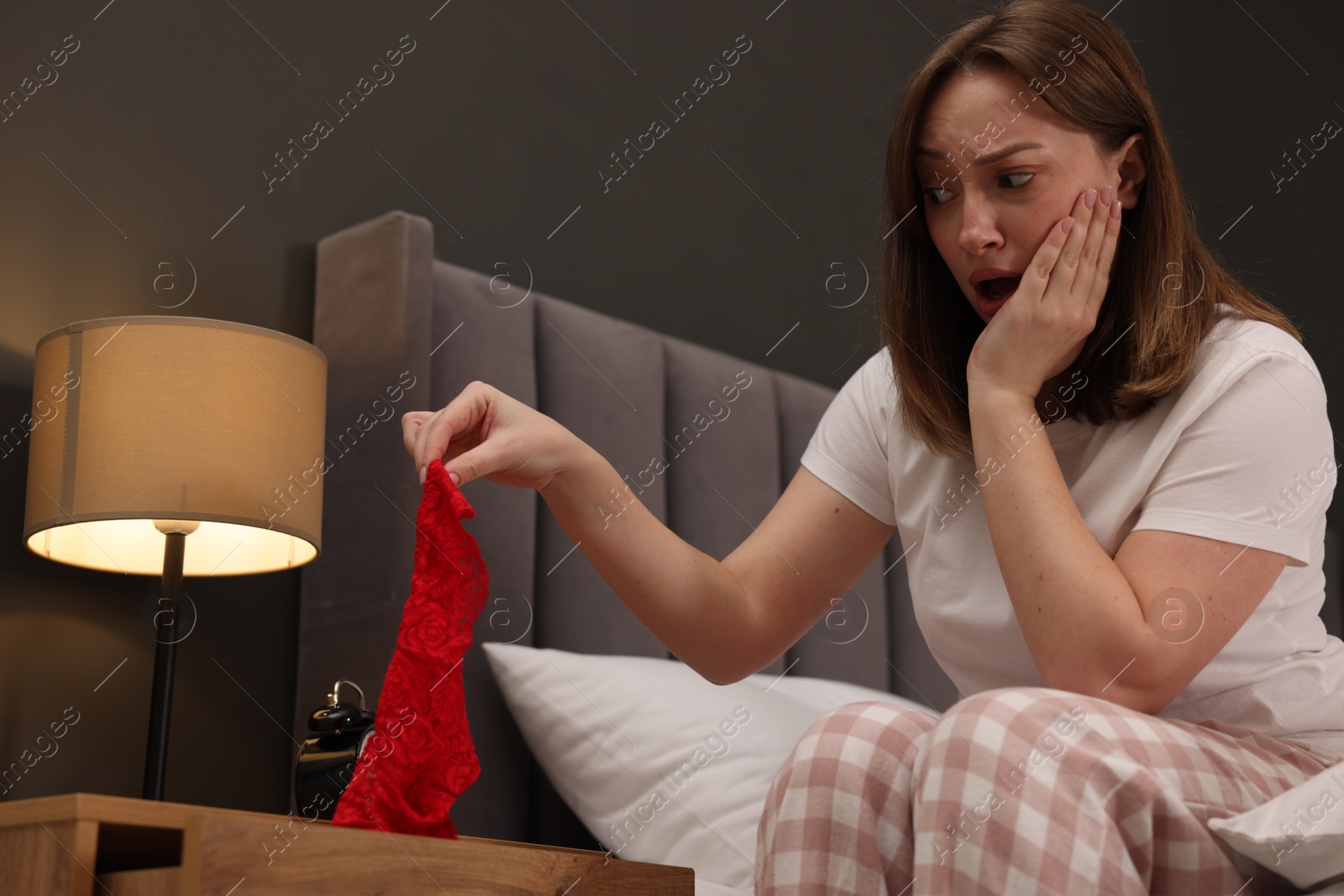 Betrayal. Shocked wife finding mistress panties on bed at home Photo of Betrayal. Shocked wife finding mistress panties on bed at home