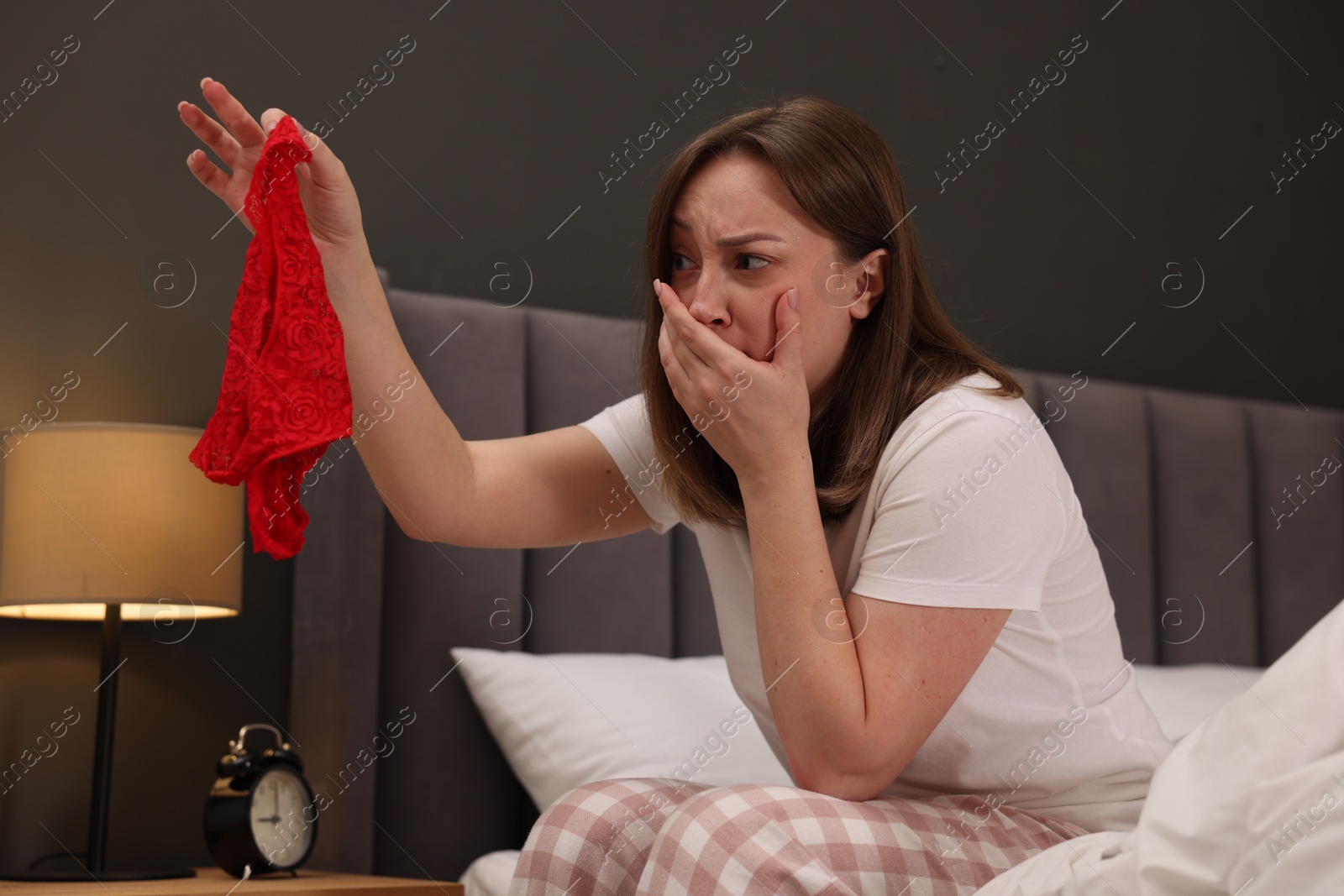Photo of Betrayal. Shocked wife finding mistress panties on bed at home