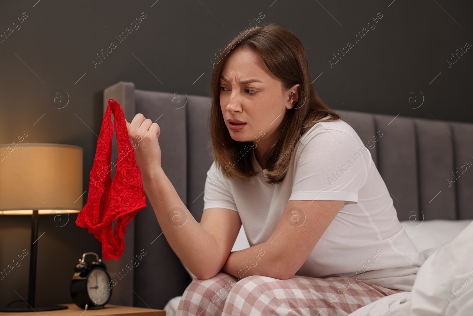 Photo of Betrayal. Frustrated wife finding mistress panties on bed at home