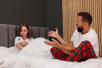 Photo of Betrayal. Upset woman ignoring her husband on bed at home