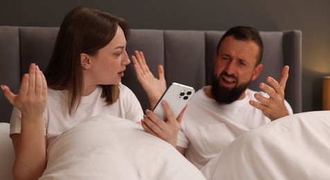 Photo of Betrayal. Couple arguing in bed at home