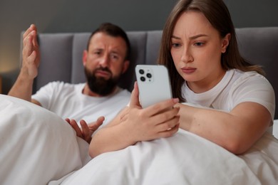 Photo of Betrayal. Couple arguing in bed at home