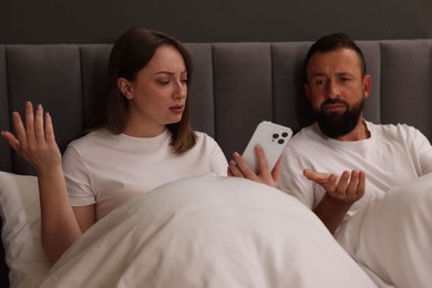 Photo of Betrayal. Couple arguing in bed at home