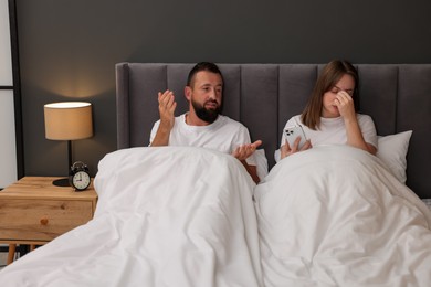 Photo of Betrayal. Couple arguing in bed at home