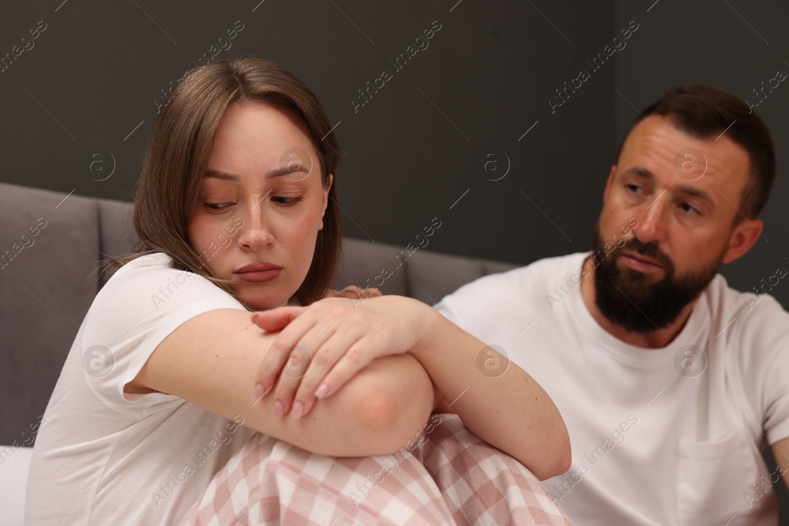 Photo of Betrayal. Offended woman ignoring her husband in bedroom