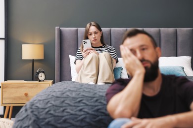 Photo of Betrayal. Jealous woman finding proofs of her unfaithful husband on smartphone on bed at home, selective focus