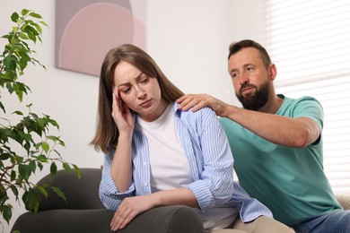 Photo of Betrayal. Husband apologizing to his offended wife on sofa at home