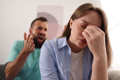 Photo of Betrayal. Angry man shouting at his frustrated wife at home, selective focus