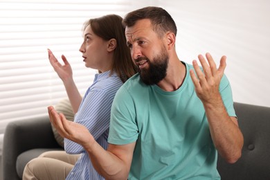 Photo of Betrayal. Emotional couple arguing on sofa at home
